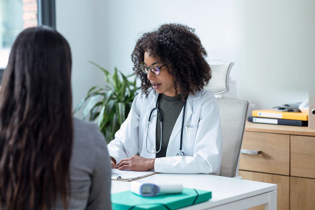 A doctor speaks to her patient as she fills out paperwork.